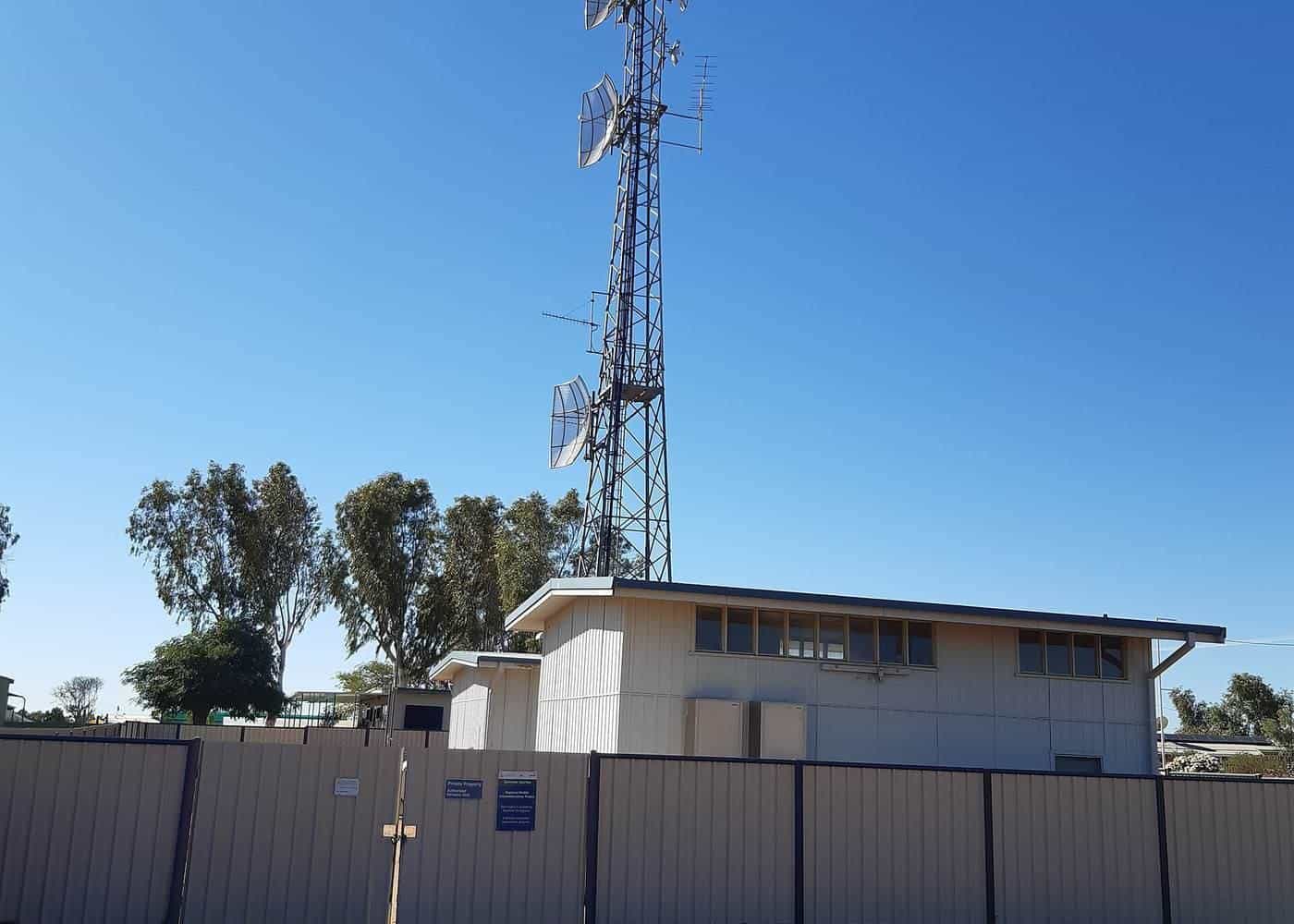 Mobile phone tower beside a building in an outback town under blue sky