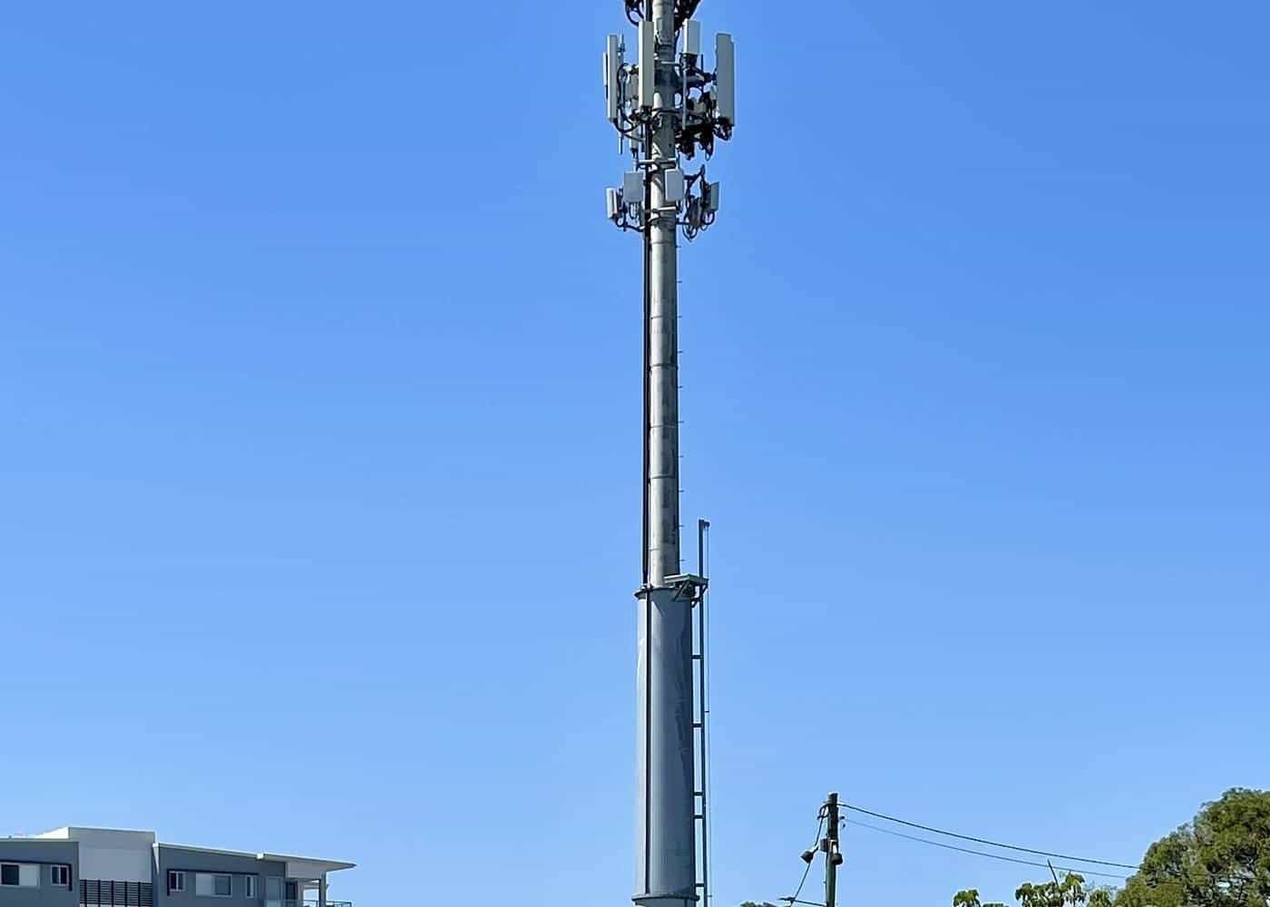 Tall mobile phone tower with antennas against a clear blue sky