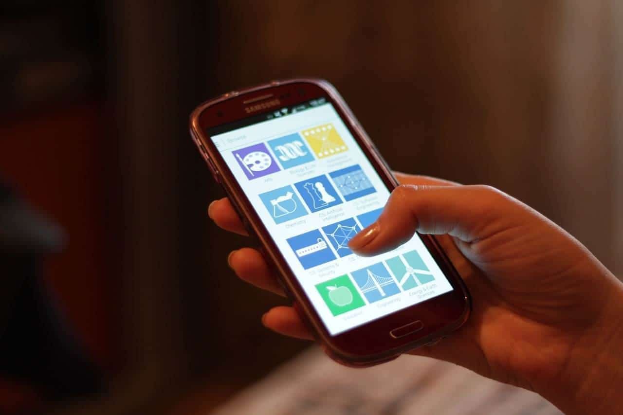 Person holding a smartphone showing app icons